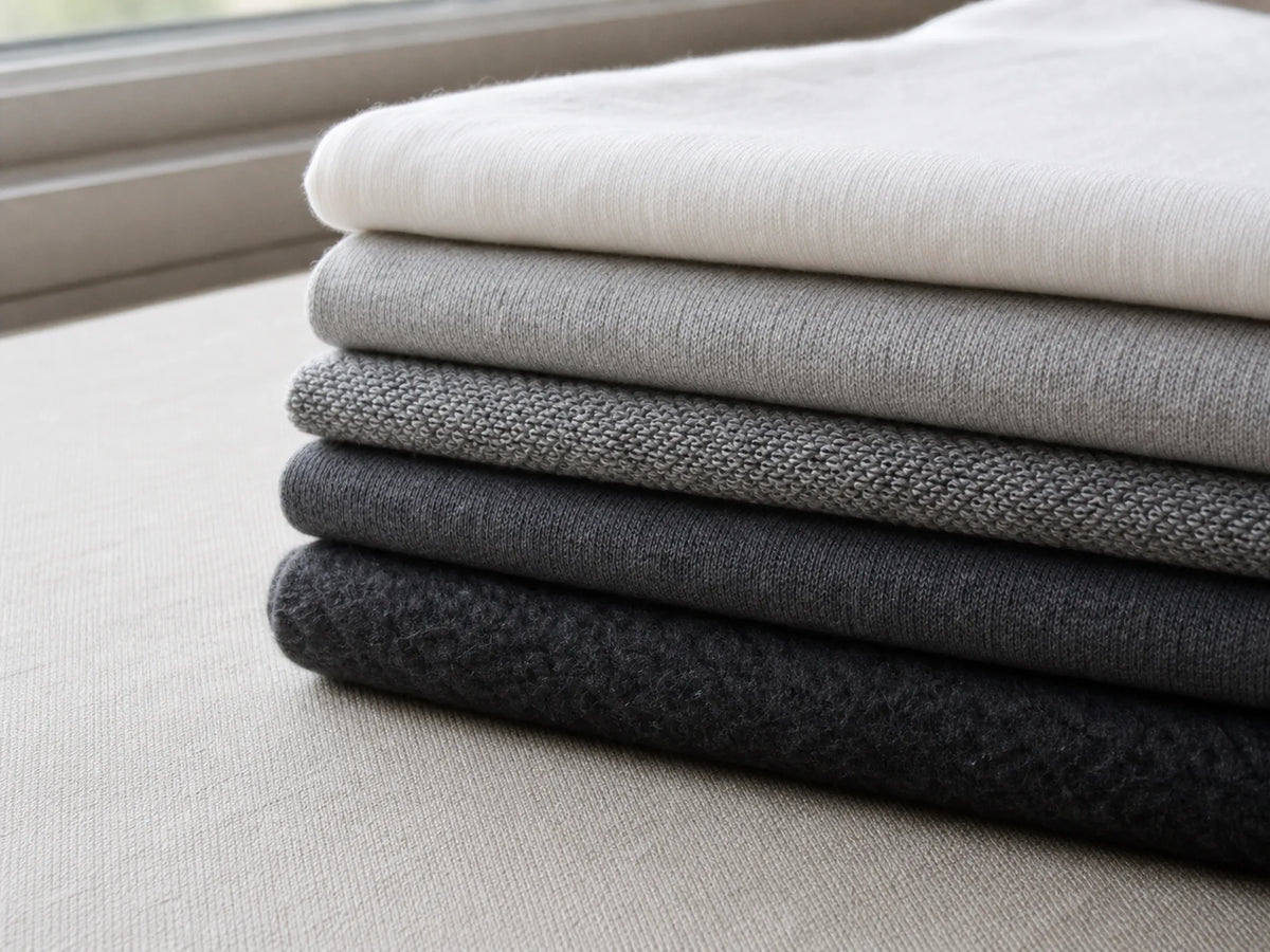 Photorealistic close-up of cotton fabric weights ranging from lightweight jersey to heavyweight brushed fleece.