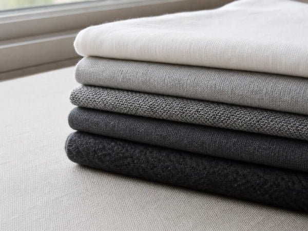 Photorealistic close-up of cotton fabric weights ranging from lightweight jersey to heavyweight brushed fleece.