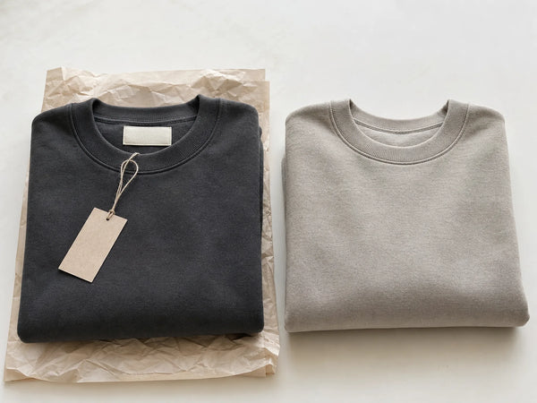 Photorealistic editorial comparison of a private-label sweatshirt with custom trims and a plain white-label sweatshirt.