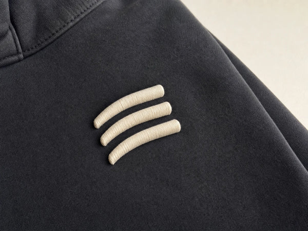 Photorealistic product mockup showing raised cream 3D puff embroidery stitches on a charcoal heavyweight hoodie.