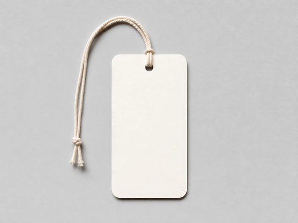 Photorealistic product mockup of a blank warm-white uncoated clothing hang tag with a cotton string viewed overhead.