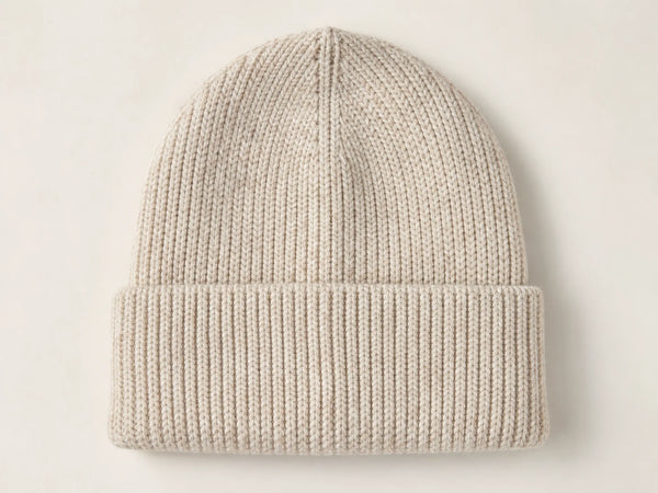 Photorealistic product mockup of a blank oatmeal heavyweight rib-knit cuffed beanie viewed overhead on an off-white background.