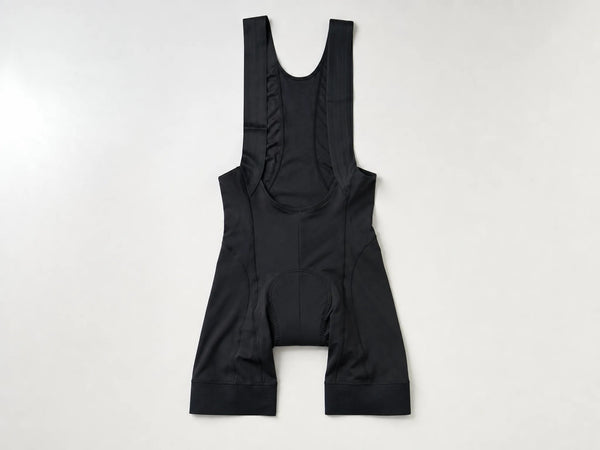 Custom black cycling bib shorts with shoulder straps, front flat lay
