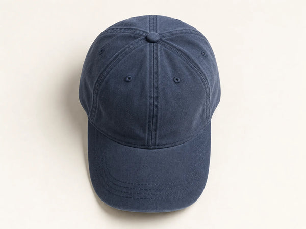 Photorealistic product mockup of a blank washed navy low-profile cotton dad cap viewed overhead on an off-white background.