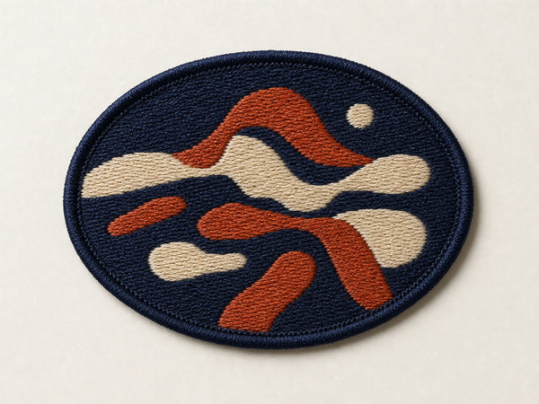 Photorealistic product mockup of an unbranded navy, rust and cream embroidered patch with visible fill stitches and a merrowed edge.