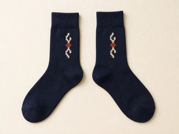 Photorealistic product mockup of navy custom jacquard crew socks with a small abstract knitted motif and no branding.