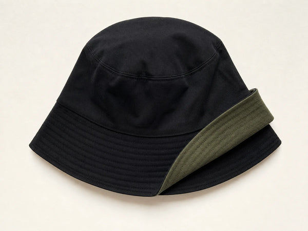 Photorealistic product mockup of a blank black and olive reversible cotton bucket hat with one brim section turned back.