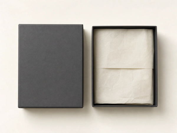 Photorealistic product mockup of a blank charcoal rigid garment box shown open with plain cream tissue and no branding.