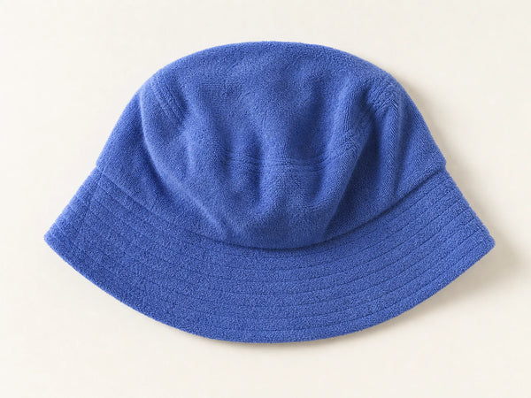 Photorealistic product mockup of a blank cobalt blue cotton terry bucket hat with visible loop texture viewed overhead.